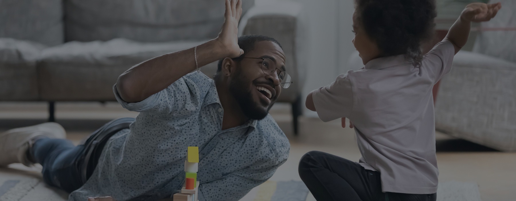 lifestyle image of a man high-fiving a child in a living room